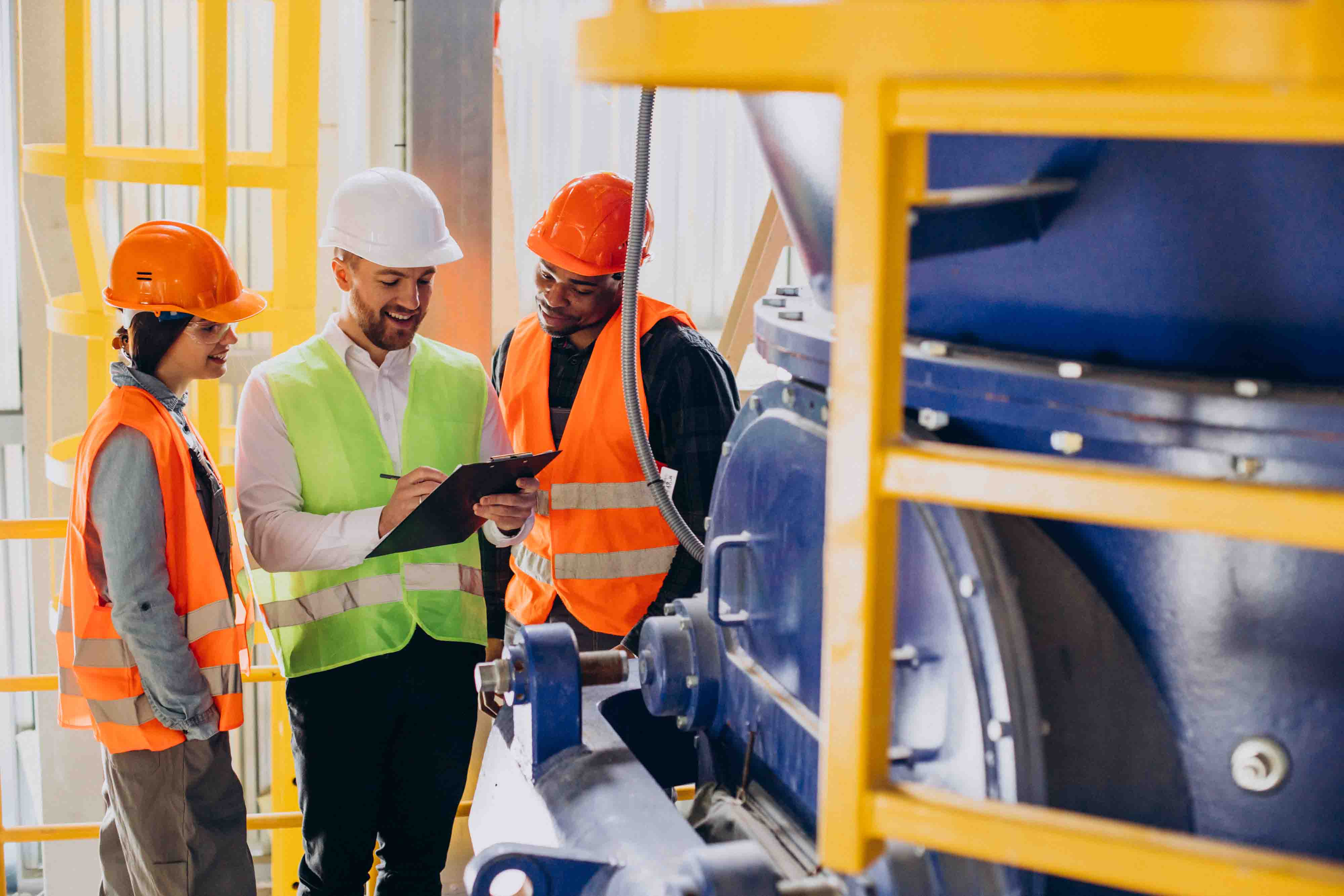 Site team in safety gear reviewing a compliance checklist beside industrial equipment